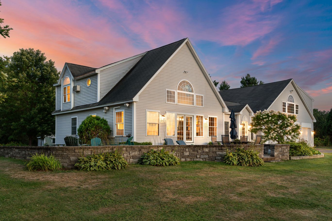 A home at twilight with warm light in the windows and a pink sky above the roofline.