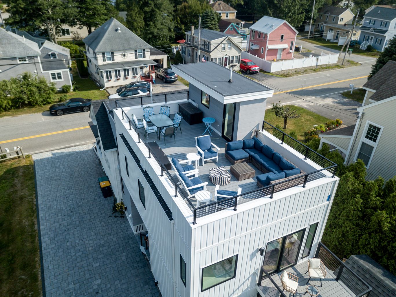Aerial view of a modern home with a rooftop deck, showing the surrounding street.