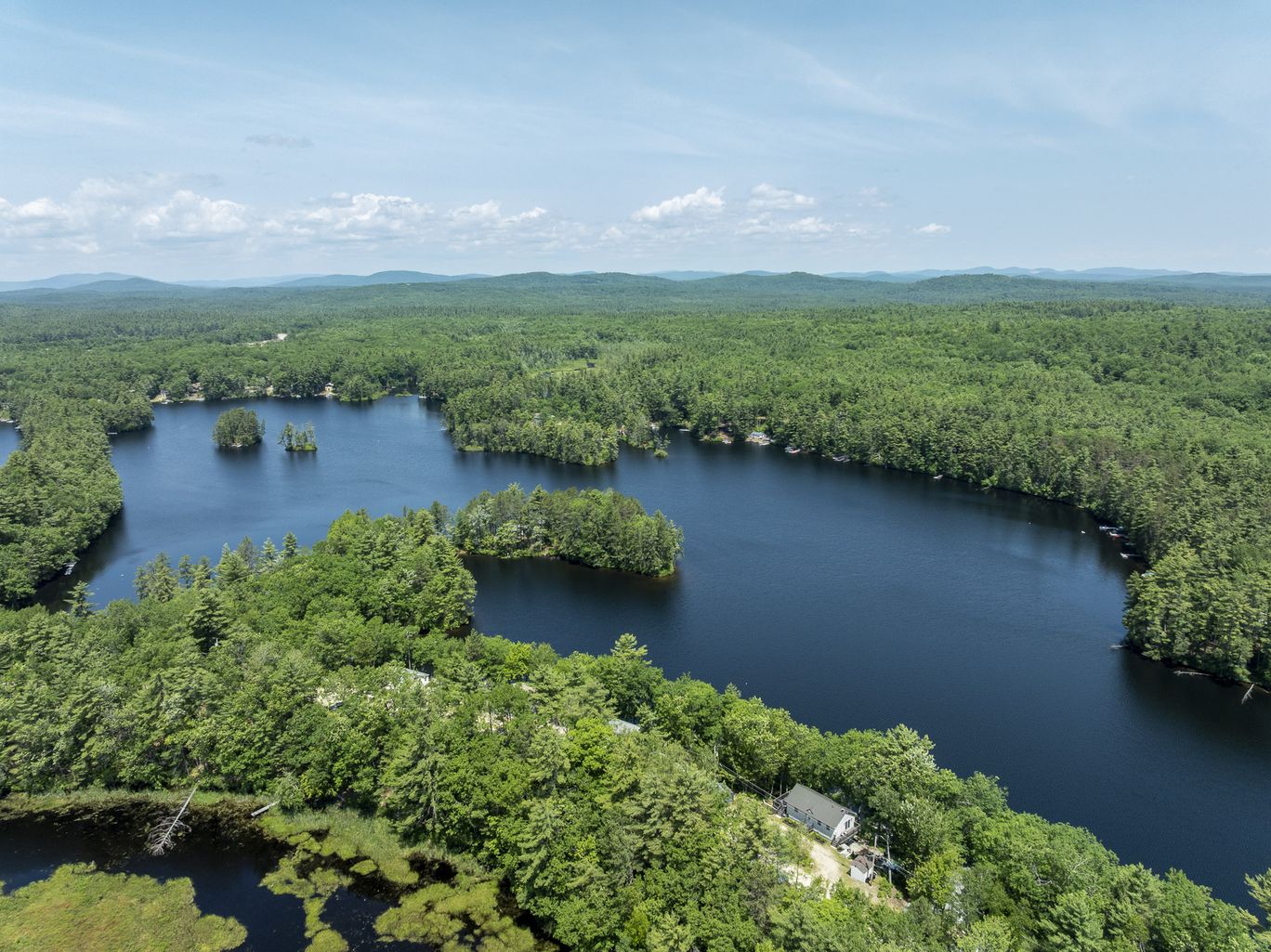 Wide aerial view of a lake surrounded by forest.