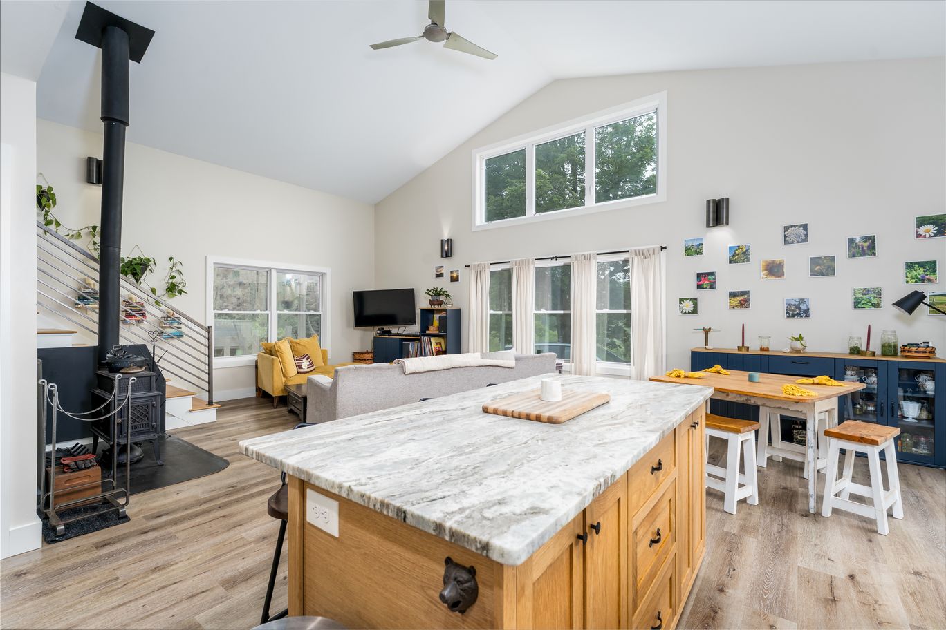 Open great room with a wood stove, a marble island, and a vaulted ceiling.