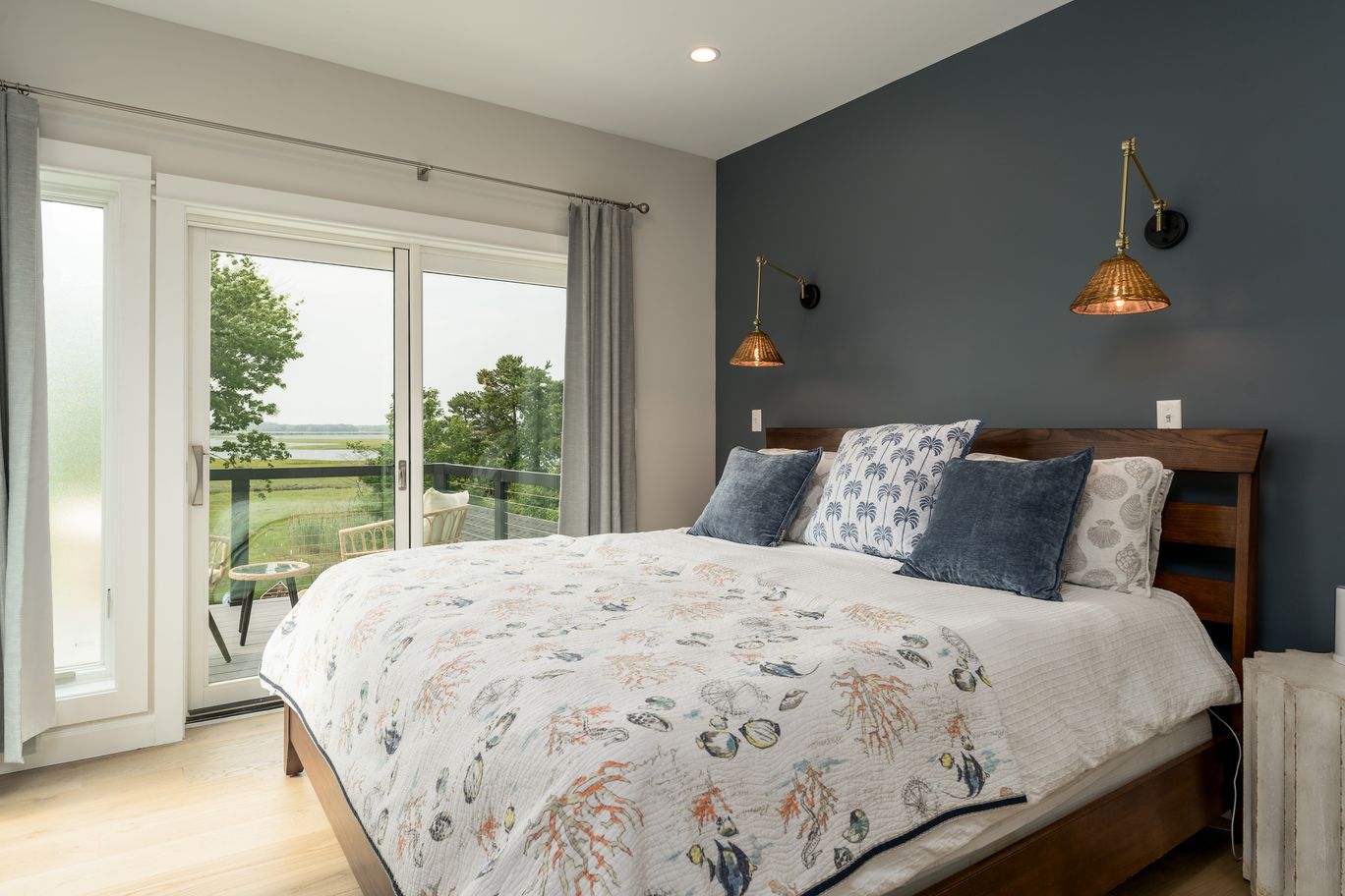 Primary bedroom with a dark accent wall and sliding doors onto a marsh view.