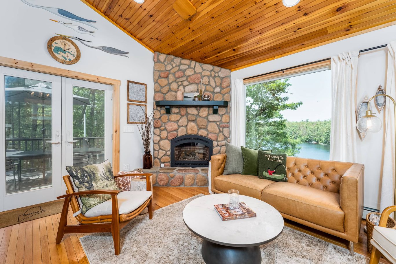 Living room with a floor to ceiling stone fireplace and a wood plank ceiling.
