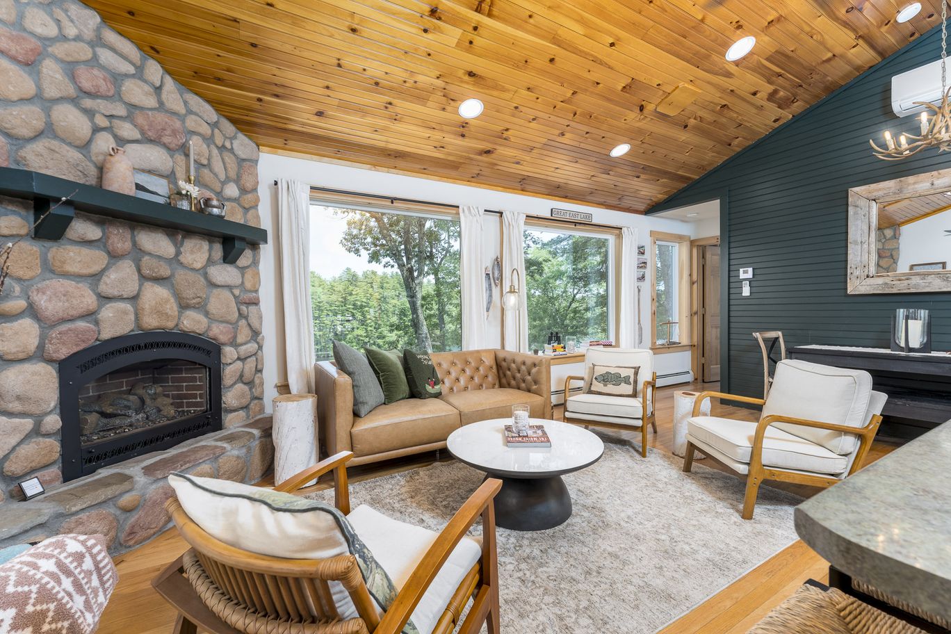 Seating area beside a stone fireplace with windows onto the water.