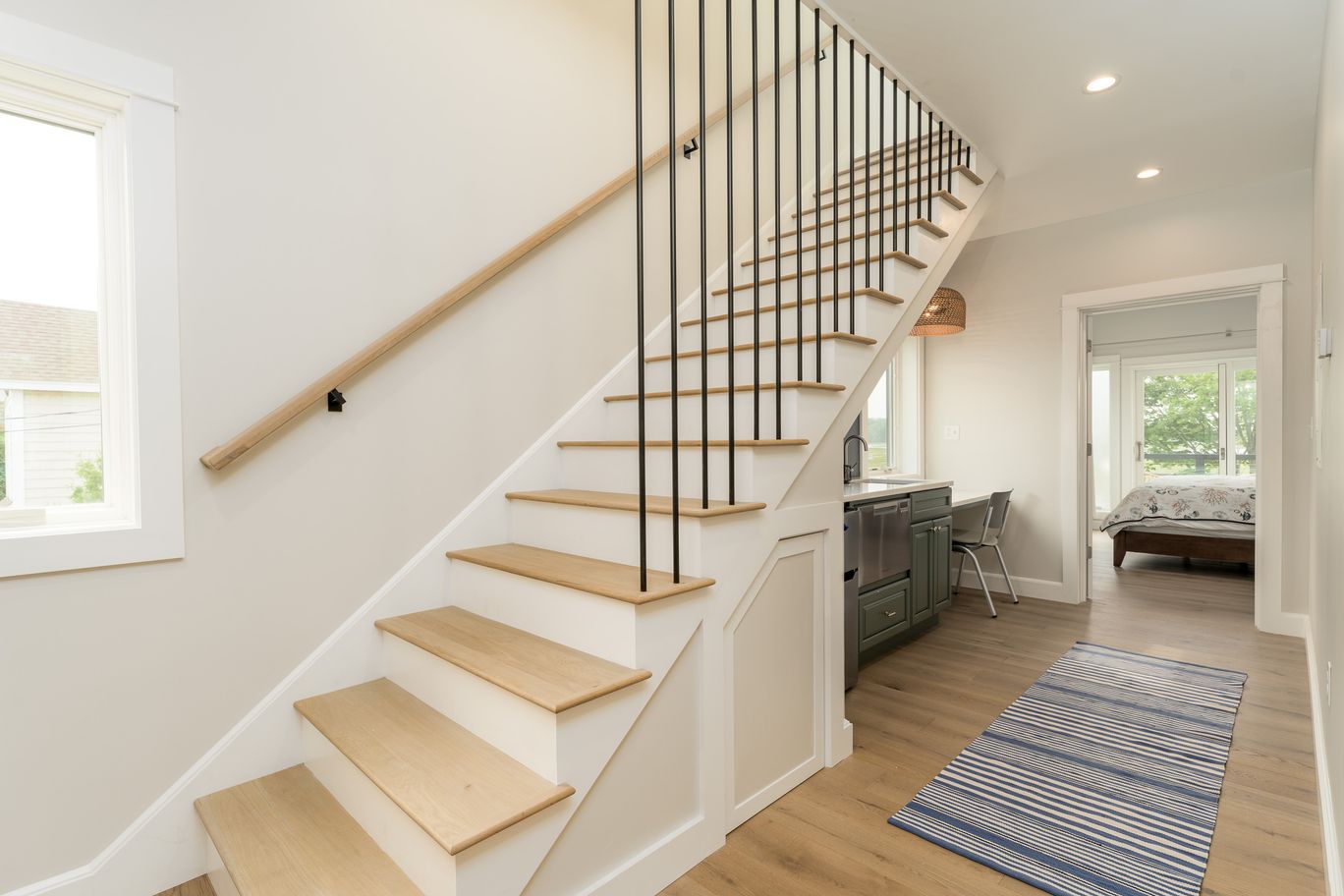 Staircase with white risers, wood treads, and a slim metal railing.