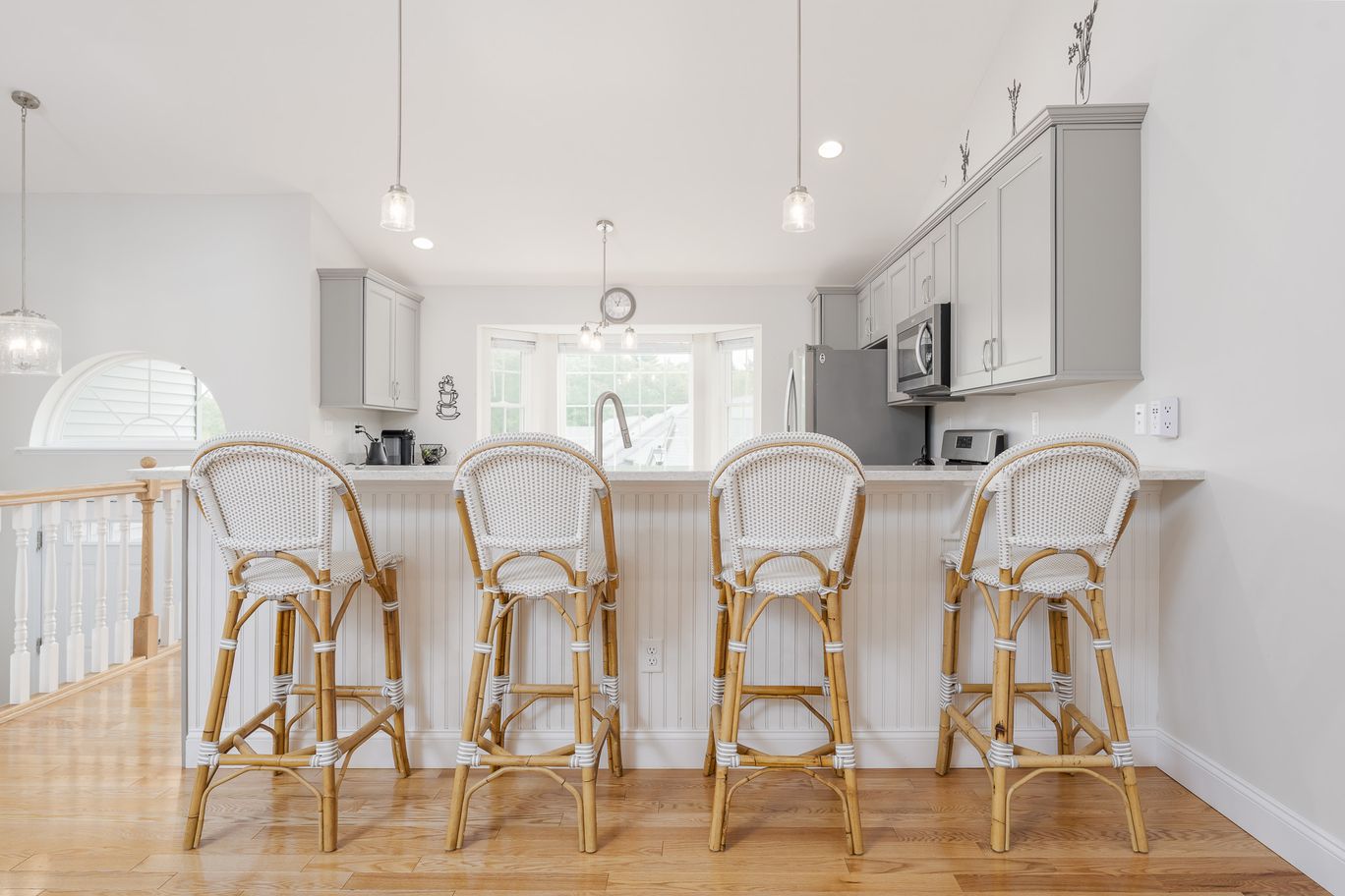 Kitchen with a white island and rattan barstools.