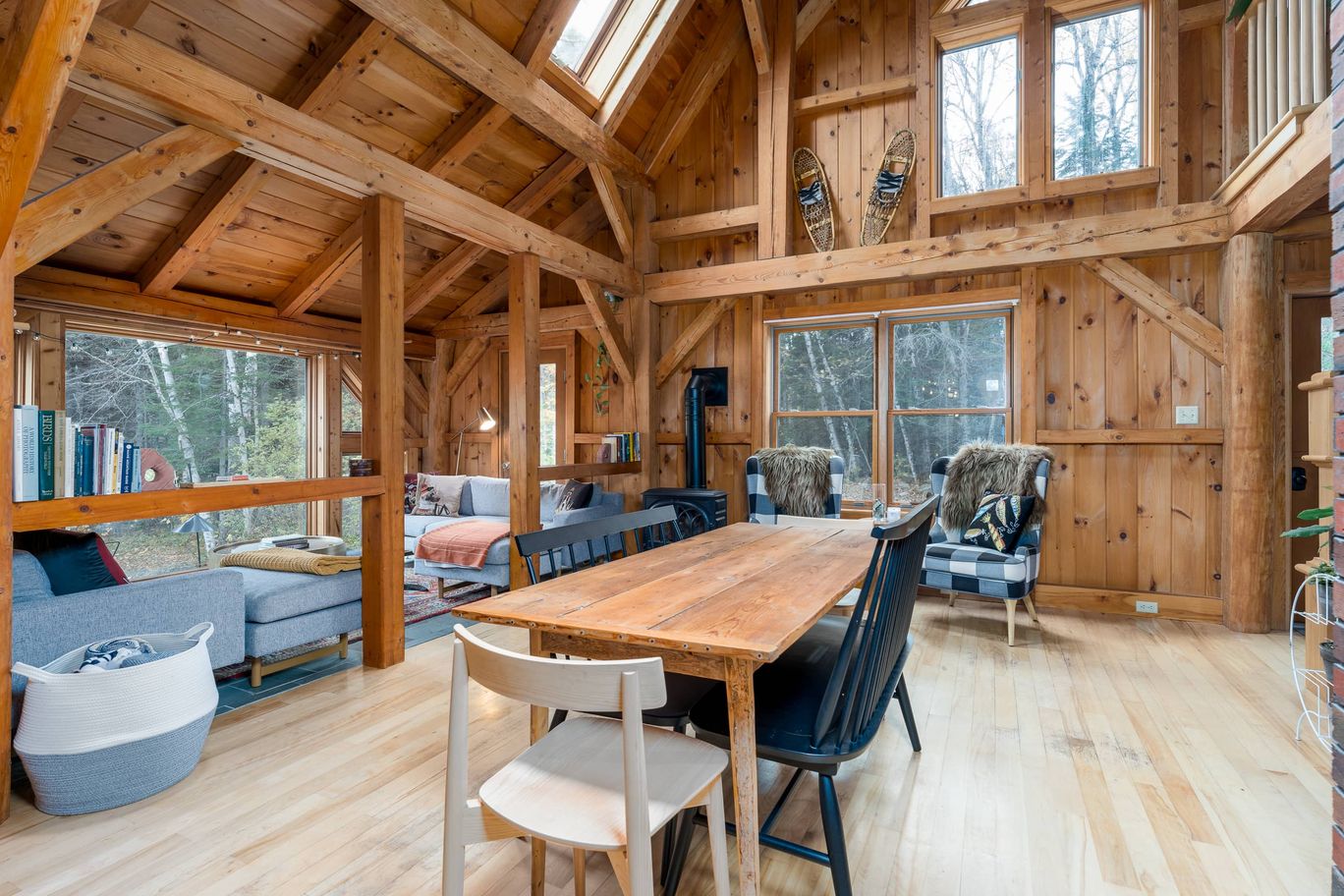 Timber frame great room with exposed beams and a long dining table.